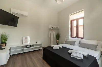 a white bedroom with a large bed and a television at Casa Chris in Chania Town