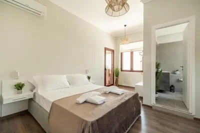 a white bedroom with a large bed and a bathroom at Casa Chris in Chania Town