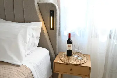 a bottle of wine on a table next to a bed at Unick Seaview Luxury Living in Kalathas