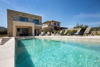 a swimming pool in front of a house at Amfitriti Villa in Gramvousá