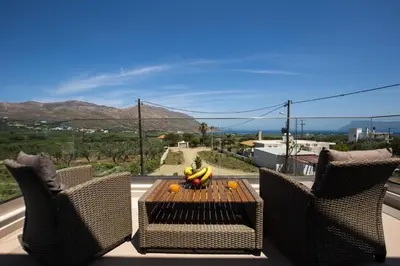a patio with two chairs and a table with bananas on it at Amfitriti Villa in Gramvousá