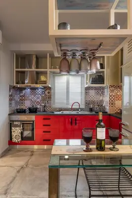 a kitchen with red cabinets and a bottle of wine at Cosy 1st floor apartment at Koum Kapi Beach in Chania Town