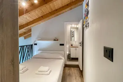 a small bedroom with a white bed and wooden ceilings at LOFTaki - Petite house next to Koum Kapi beach in Chania Town