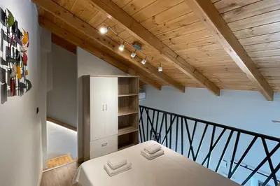 a room with a bed and a balcony with wooden ceilings at LOFTaki - Petite house next to Koum Kapi beach in Chania Town