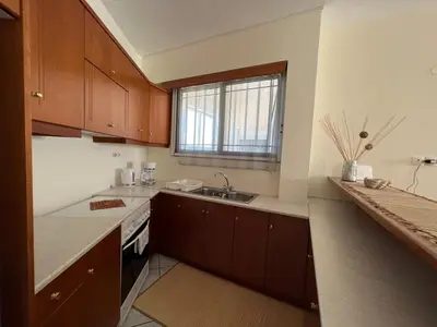 a kitchen with wooden cabinets and a sink and a window at Aria Aparment in Palaiochóra