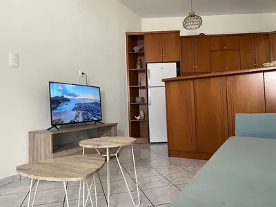 a kitchen with two stools and a tv and a refrigerator at Aria Aparment in Palaiochóra