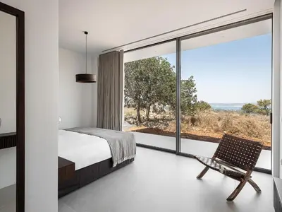 a bedroom with a bed and a chair and a large window at Nature & Beauty Villa in Xirostérnion