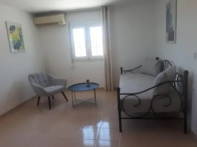 a bedroom with a bed and a chair and a table at Cozy SeaView Apartment Walking Distance to Beach in Akhatzikiá