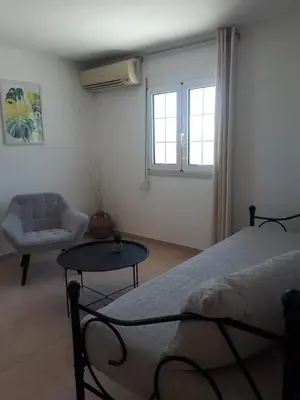 a bedroom with a bed and a chair and a table at Cozy SeaView Apartment Walking Distance to Beach in Akhatzikiá