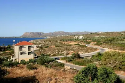 a road and a house on a hill next to the water at Cozy SeaView Apartment Walking Distance to Beach in Akhatzikiá