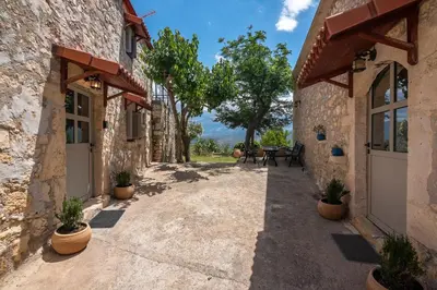a stone building with doors and potted plants at Aptera Verde - Stone Cottages Complex in Áptera