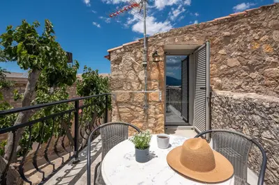 a table with a hat sitting on a balcony at Aptera Verde - Stone Cottages Complex in Áptera