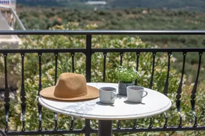 a hat and two cups on a table on a balcony at Aptera Verde - Stone Cottages Complex in Áptera