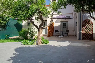 a tree in front of a house with an umbrella at Roidis Apartments -close to city in Chania Town