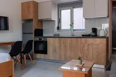 a kitchen with wooden cabinets and a table and chairs at Roidis Apartments -close to city in Chania Town