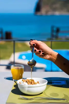 a person holding a spoon over a bowl of cereal at Elia Agia Marina Hotel in Agia Marina Nea Kydonias