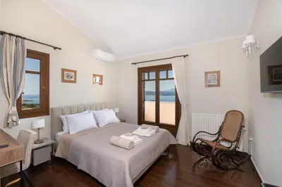 a bedroom with a bed and a chair and a window at Marathi Hilltop Oasis Sea View Villa in Marathi
