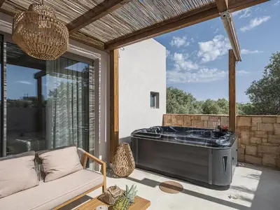 a large tub on a patio with a couch at Vanilla Suites with Hot Tub in Daratso