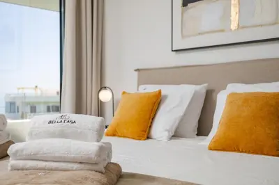 a bed with white and orange pillows and a window at Bella Casa - Newly Built Designer Villa in Kalyves