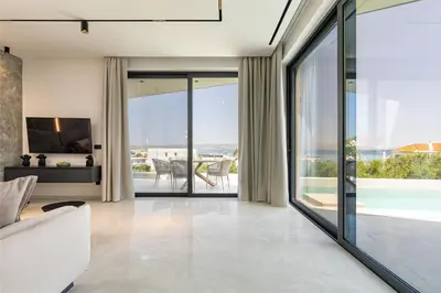 a living room with sliding glass doors and a view of the ocean at Bella Casa - Newly Built Designer Villa in Kalyves