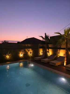 a swimming pool with lounges and palm trees at night at Memoire Guest House I Private Heated Pool I 200m beach in Chania Town