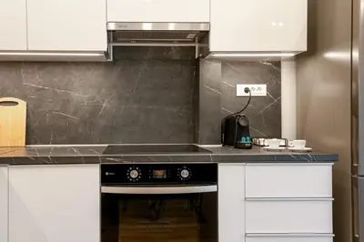 a kitchen with white cabinets and a black stove at Artemis Apartments in Chania Town