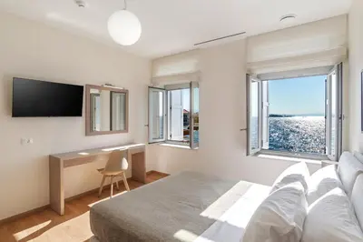a bedroom with a bed and a desk and windows at Kormoranos-Hydrobates Waterfront Villa in Chania Town
