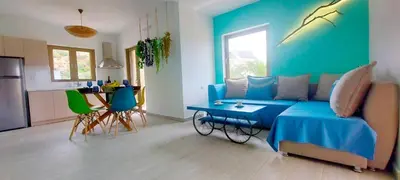 a living room with a blue couch and a kitchen at Umoya in Palaiochóra
