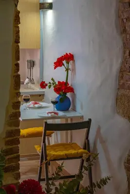 a room with a table with a vase with red flowers at Mythos -Old Town-Old harbour Chania in Chania Town