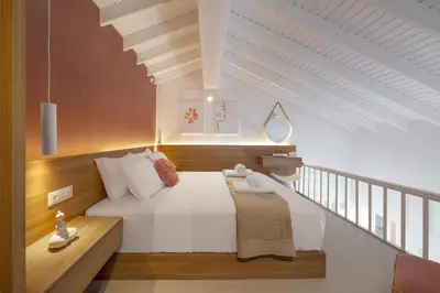 a bedroom with a large white bed with a staircase at Stavros Beachfront Suites in Agia Marina Nea Kydonias