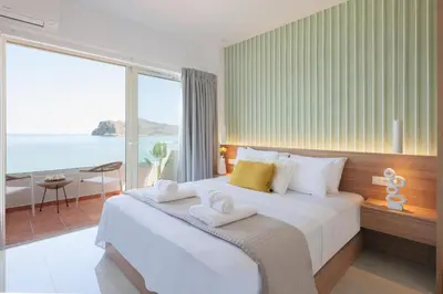 a bedroom with a large bed with a view of the ocean at Stavros Beachfront Suites in Agia Marina Nea Kydonias