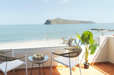 a balcony with chairs and a view of the beach at Stavros Beachfront Suites in Agia Marina Nea Kydonias