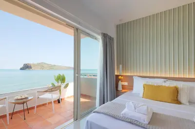 a bedroom with a bed and a view of the ocean at Stavros Beachfront Suites in Agia Marina Nea Kydonias