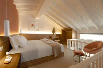 a bedroom with a white bed and a staircase at Stavros Beachfront Suites in Agia Marina Nea Kydonias