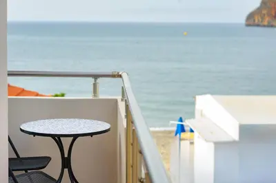 a table on a balcony with a view of the beach at Stavros Beachfront Suites in Agia Marina Nea Kydonias