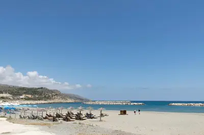 a beach with chairs and umbrellas and the ocean at kolymvari4you in Kolymvari