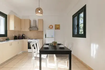 a kitchen with a black table and white chairs at Theodoras Villas in Gavalochori