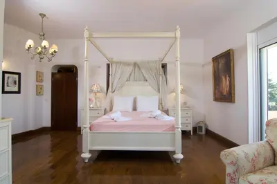 a bedroom with a white canopy bed with pink sheets at Villa Ektor in Kissamos