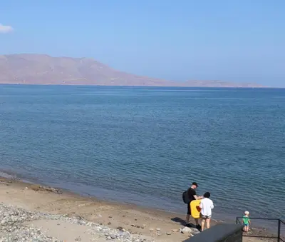 a group of people standing on a beach near the water at Ponente - seaside stone house in Kissamos