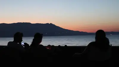 a group of people sitting on the beach watching the sunset at Ponente - seaside stone house in Kissamos
