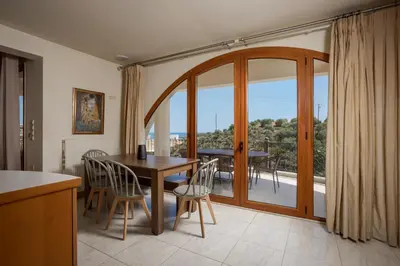 a dining room with a table and chairs and a balcony at Zen Maisonette Retreat in Daratso