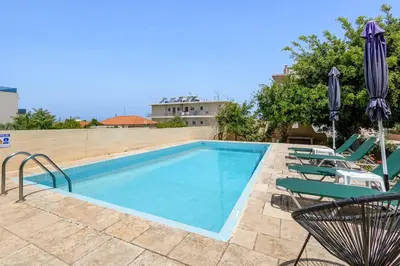 a swimming pool with lawn chairs and umbrellas at 6622 Luxury Apartment with Shared Pool in Chania Town