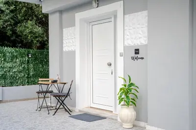 a white door with a plant next to a table at Kamari Apartment - Chania in Chania Town