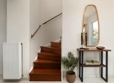 a hallway with a staircase with a mirror and a console table at Pithos Apartment in Korakiaí