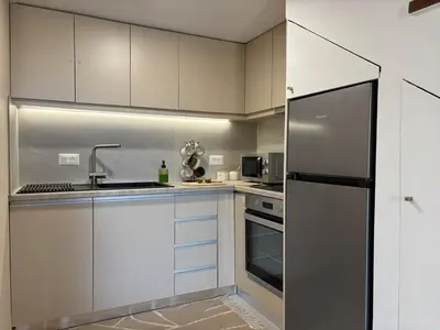 a kitchen with white cabinets and a stainless steel refrigerator at Batann Apartment in Palaiochóra