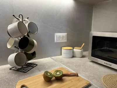 a kitchen with a cutting board and cups and a microwave at Batann Apartment in Palaiochóra