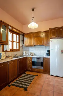 a kitchen with wooden cabinets and a white refrigerator at Mountain View Villa, by the Pool,Aris in Próvarma