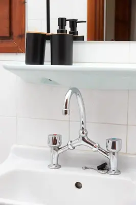 a kitchen sink with a faucet with two cups on a shelf at Lyria Hotel Apartments in Stalos