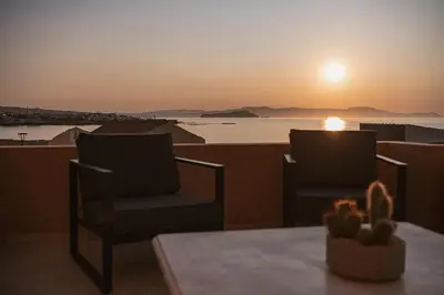 two chairs and a table on a balcony with a sunset at Aeri Residence in Chania Town