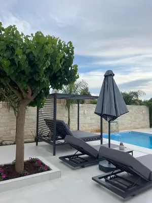 a patio with chairs and a tree next to a pool at Amare suite 2 in Perivólia